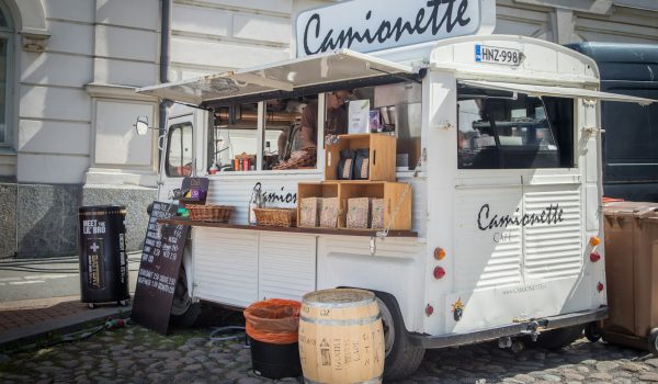 white and black food truck parked near white concrete building during daytime