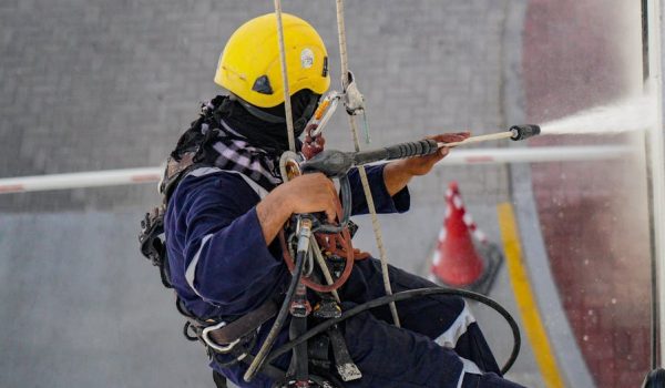 Person in Yellow Helmet Using a Power Spray