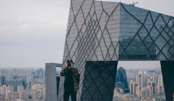 man taking picture while standing near gray building during daytime