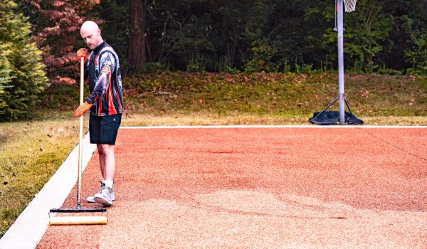 a man standing on a basketball court holding a stick