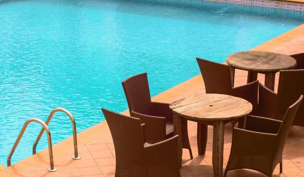 wooden cafe table and chairs beside inground pool