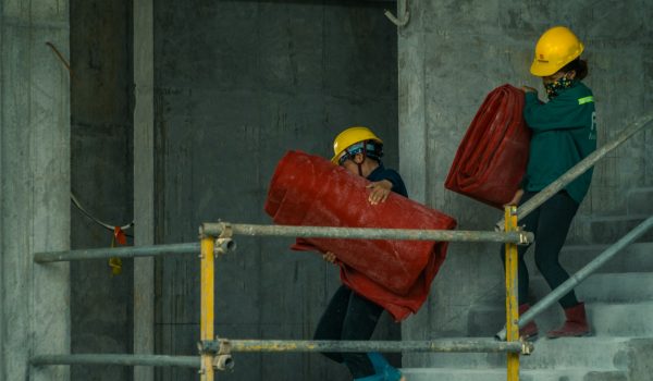 man in orange hard hat holding red plastic bag